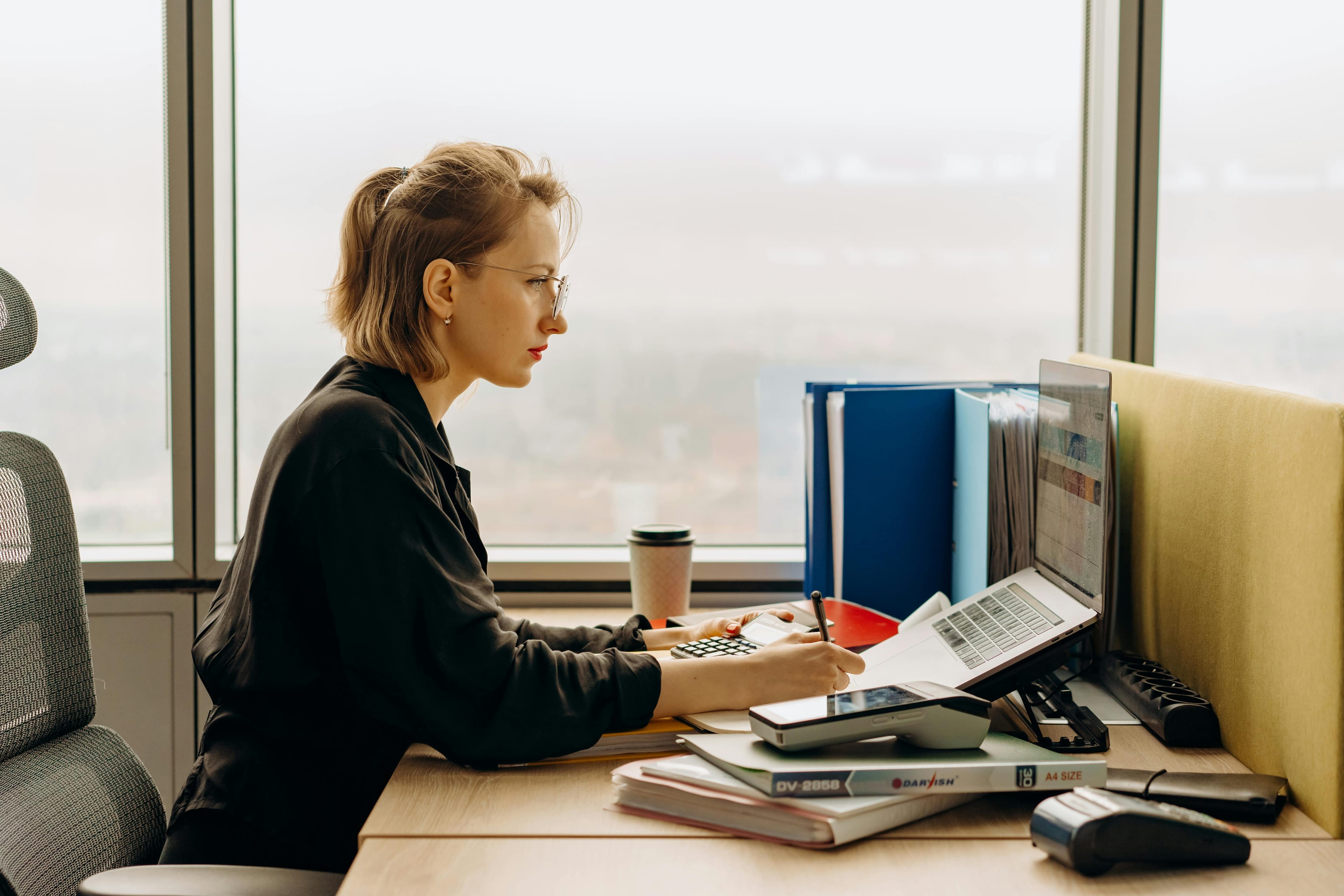 Accountant reviewing records at a desk with a laptop and calculator